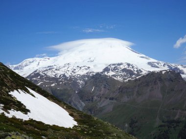 Büyük doğa sıradağları. Beyaz kar dağı veya yeşil alanlar, mavi gökyüzü arka plan ile volkan Elbrus amazing perspektif. Elbrus manzara görünümü - Rusya ve Avrupa'nın en yüksek zirvesi