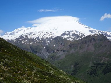 Büyük doğa sıradağları. Beyaz kar dağı veya yeşil alanlar, mavi gökyüzü arka plan ile volkan Elbrus amazing perspektif. Elbrus manzara görünümü - Rusya ve Avrupa'nın en yüksek zirvesi