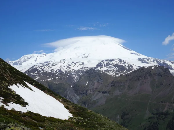 Great Nature bergskedjan. Amazing perspektiv kaukasiska Snow Mountain eller Volcano Elbrus med gröna fält, blå himmel bakgrund. Elbrus landskap View-den högsta toppen i Ryssland och Europa — Stockfoto
