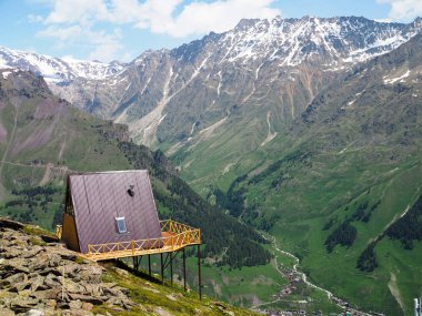 Güneşli bir günde yeşil vadinin güzel bir görünümü ile dağların yüksek bir tepe üzerinde kırmızı bir çatı ile tek ahşap ev