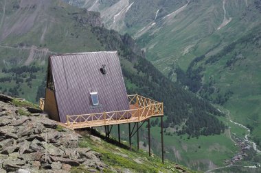 Güneşli bir günde yeşil vadinin güzel bir görünümü ile dağların yüksek bir tepe üzerinde kırmızı bir çatı ile tek ahşap ev