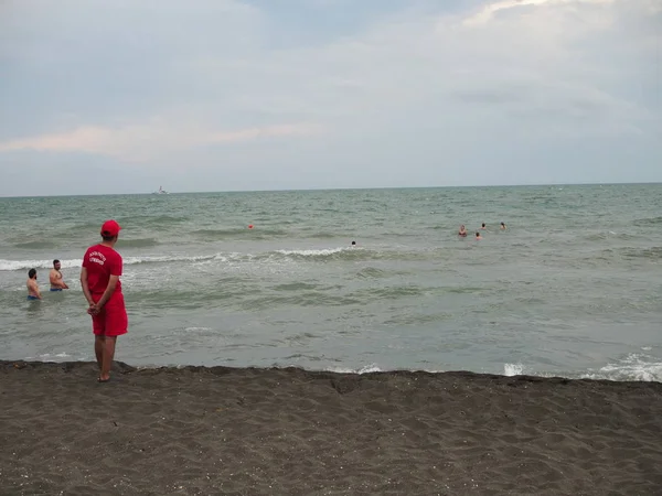 Salvavidas en la costa del mar observando a los bañistas en la tormenta por los turistas. Georgia, Ureki - junio 2019 — Foto de Stock
