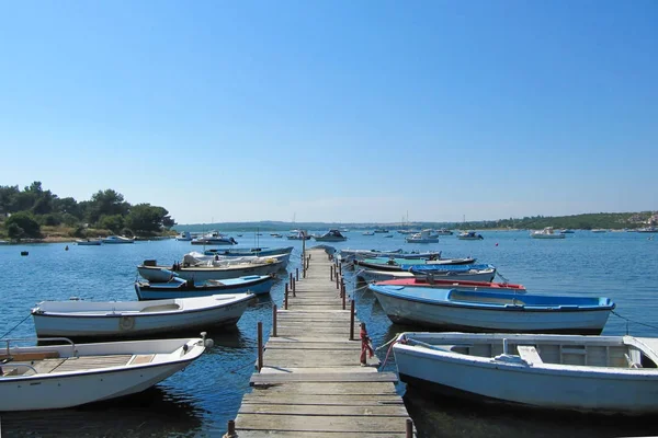 Muchos barcos atados a un muelle de madera con una hermosa vista del lago. Croacia, Istra, Medulin - Julio, 2010 . — Foto de Stock