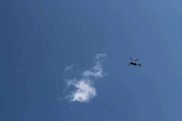 Militär helikopter och ett vitt moln i den blå himlen. Begreppet fredlig himmel — Stockfoto