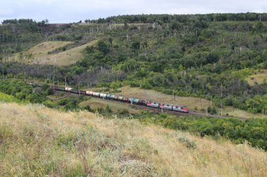 Çift yığın kargo konteynerleri yüklü uzun bir tren dağ kırsalında sıkı s-eğrileri etrafında yolunu rüzgarlar. Kaldırılan tüm Kimlik işaretleri.