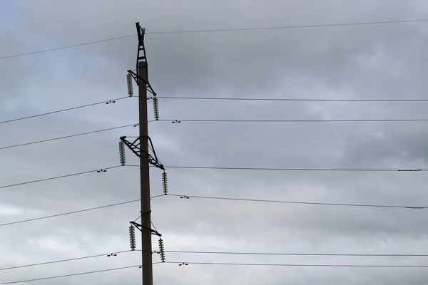Transmisión de energía eléctrica. La parte superior de la torre de alta tensión contra el cielo nublado . —  Fotos de Stock