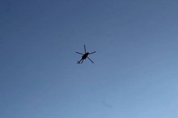 Grande helicóptero militar paira no céu. Um helicóptero camuflado voa em alta velocidade . — Fotografia de Stock