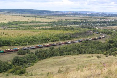 Çift yığın kargo konteynerleri ile yüklü uzun bir tren dağ kırsalında sıkı s-eğrileri etrafında yolunu rüzgarlar.