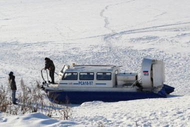 Hovercraft on frozen river: Driver communicates with passengers Russia, Saratov-January, 2018 clipart