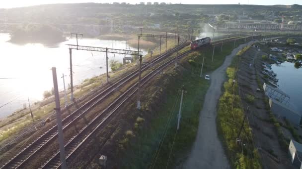 Oroszország, Saratov - június, 2020. Légi repülő mozdony húzza át a hidat a folyón naplementekor — Stock videók