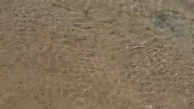 Sarı kum, berrak dalgalı nehir suyundan görülebilir. Kristal berraklığında. Nehrin dibindeki kum. Doğal bir kaynak olarak suyun korunması ve korunması. Küçük dalgalar