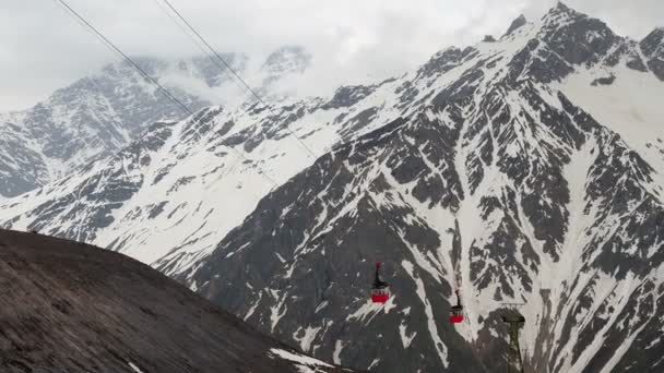 Röd linbana på bakgrunden av berg täckt med snö. Flygfotografering — Stockvideo