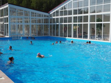 İnsanlar yaz aylarında kayak merkezinin pitoresk manzarasına karşı açık havuzda yüzerler..
