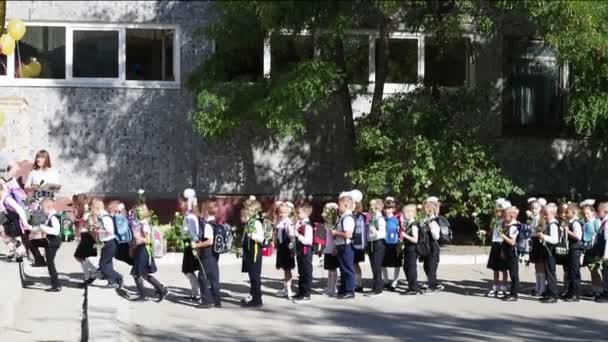 Ryssland, Saratov - 01 september 2020: förstaklassare med ballonger och flaggor går första lektionen i skolan den 1 september. — Stockvideo