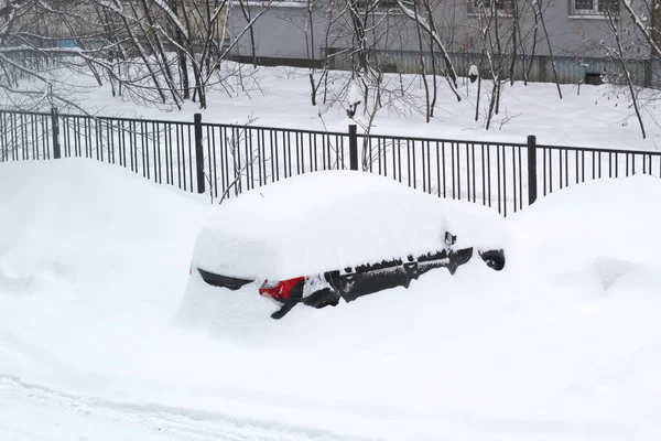 Samochód jest prawie całkowicie pokryty śniegiem na podwórku przed ogrodzeniem.. — Zdjęcie stockowe