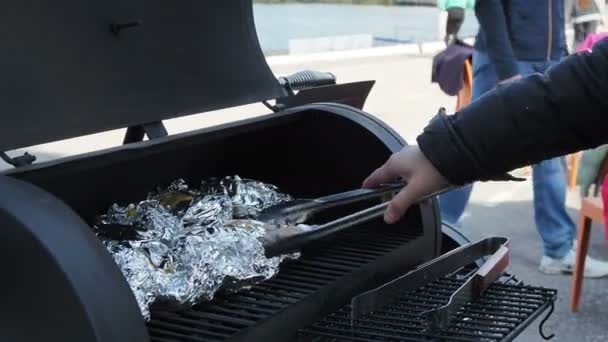 Gotowanie domowe - Rozpakowywanie ziemniaków pieczonych lub gotowanych na grillu gazowym zawiniętym w folię aluminiową z plasterkiem cebuli, masła i przypraw, takich jak sól i pieprz. — Wideo stockowe