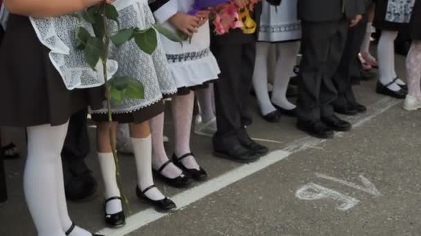 彼の手に花の花束を持つ女の子の小学校 彼女の足と白いパンスト 靴下やストッキングで靴 学校の庭でのイベントは 学年の初めに ロシア — ストック動画