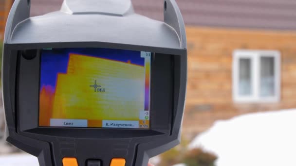 Wärmebildkamera aus nächster Nähe. Wärmeverluste zu suchen. Kampf gegen Hitzeschäden. Energiesparen. das Holzhaus auf dem Hintergrund. — Stockvideo