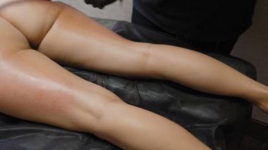 İnce kadın spa salonunda yatarken lpg aleti ile bacaklarına ve kalçalarına vakum masajı yapıyor. Genç kadının güzel bir figür kozmetoloji prosedürü. 4k