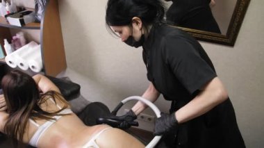 İnce kadın spa salonunda yatarken lpg aleti ile sırt ve yanlar vakum masajı alıyor. Genç kadının güzel bir figür kozmetoloji prosedürü. 4k
