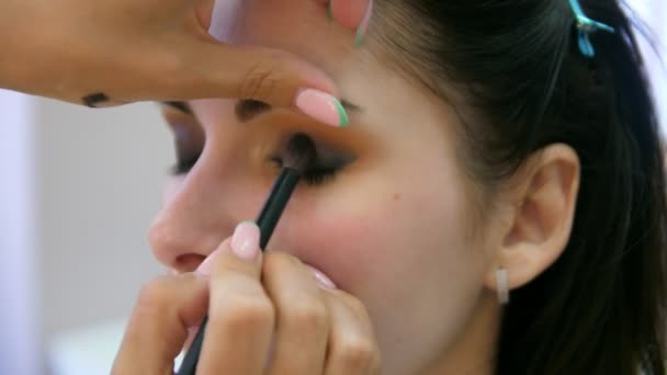 Ręce makijażu artysty stosowane makijaż na twarzy młodej kobiety. Dziewczyna robi makijaż oczu w profesjonalnym salonie. Wieczorny makijaż. Smokey oczy. 4K — Wideo stockowe