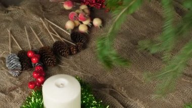 Bir Noel kompozisyonu oluşturuyor. Masaya yeşil, taze ladin dalları koy. Dekorasyon için hazırlık. Soldan sağa kamera hareketi, yakın.