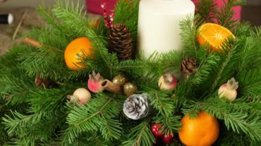 Bir masa Noel kompozisyon oluşturulması. Ladin, koni ve mandalina bir mum çubuğu üzerinde Noel oyuncakları ile Geçiş çerçevesi. Yakın çekim