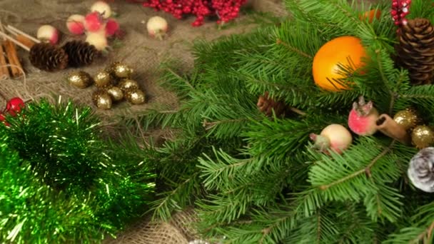 テーブルクリスマスの構成の作成。女性の手はクリスマスツリーの枝の組成を飾ります。新年のフロリスティックス。下から上へのフレームの動き。クローズアップ — ストック動画
