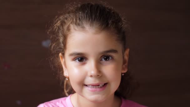 Portrait of a child girl with a sad face, smiling fervently toothless smile. To show the absence of teeth. — Stockvideo