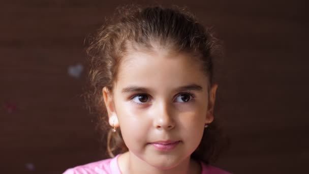 Portrait of a child girl with a mischievous cheerful face. The child shows his tongue through the hole in his teeth. To show the absence of teeth. — Stockvideo