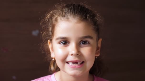 Retrato de uma menina com um sorriso sem dentes. A criança mostra a língua através do buraco nos dentes. Para mostrar a ausência de dentes . — Vídeo de Stock