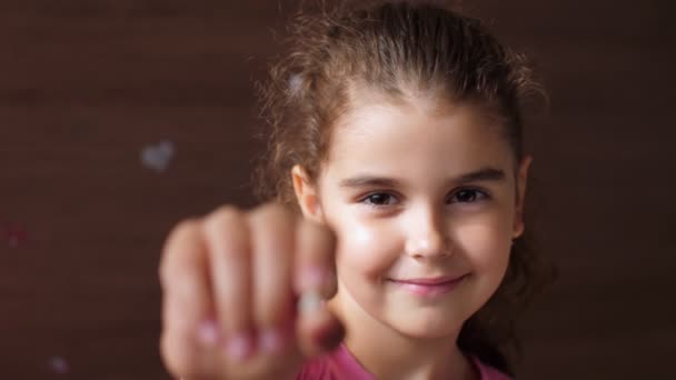 Портрет маленькой девочки с беззубой улыбкой. Показывает вырванный зуб в камеру в протянутой руке. Сдвинь фокус от зуба к лицу . — стоковое видео