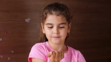 Kız çocuğu kıskaçlı bir yumruk açar ve içeriğine şaşırır. Tamamen açık, şaşırmış gözler. İlk kaybedilen süt dişleri.