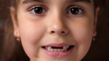 Bebek dişleri. Dişsiz gülümseme. Kök dişi kesiyorum. Kız dudaklarını açıyor ve ön dişlerini göstermiyor. Kapat.