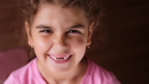 Retrato de uma menina com um sorriso sem dentes. A criança ri-se muito. Não mostrar dentes . — Vídeo de Stock