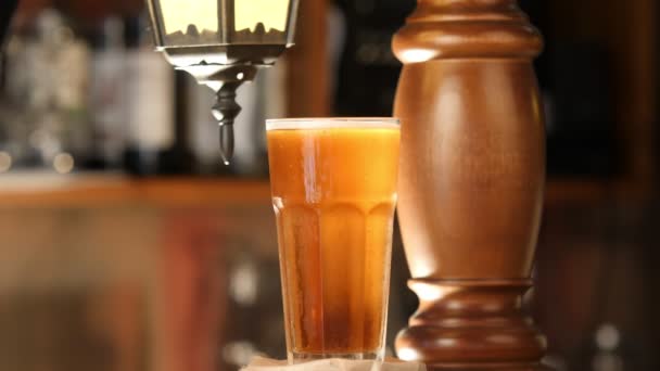 La copa de vidrio con cerveza fría gira sobre el fondo de la barra. Un vaso de cerveza facetado está en el bar en el pub. — Vídeo de stock
