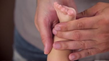 Masör bebeğe bir masaj yapar. Masörlerin elleri bebek ayaklarını yoğuruyor. Çocukların rahatlatıcı ses tonuna masaj. yakın plan