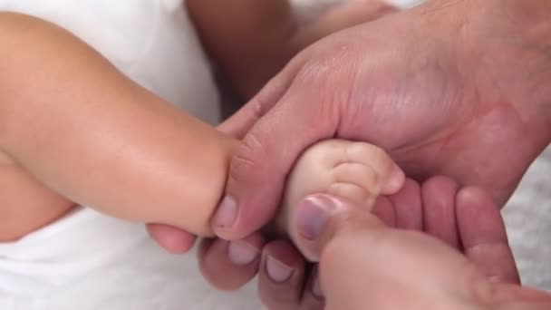 O massagista dá uma massagem ao bebê. As mãos dos massagistas estão a amassar os dedos dos pés dos bebés. Massagem para crianças aliviando o tom. Procedimento terapêutico. close-up — Vídeo de Stock