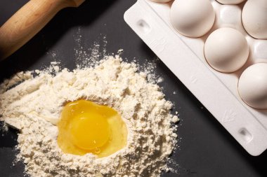 Kırık yumurta un yanında bir oklava ve tüm yumurta