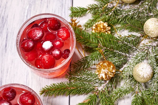 Óculos com suco de cranberry em fundo de madeira branca com ramo de pinho no fundo. Árvore Natal — Fotografia de Stock