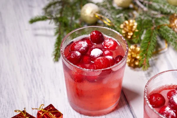 Glasses with cranberry juice on white wooden background with pine branch in the background. Christmas tree