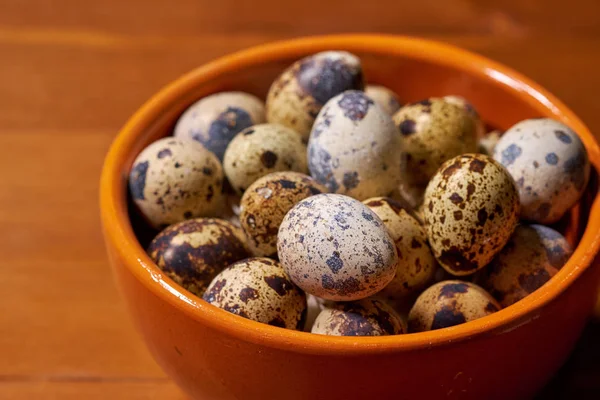 Quail eggs in clay bowl on brown wooden background. Selective focus — Stock Photo, Image