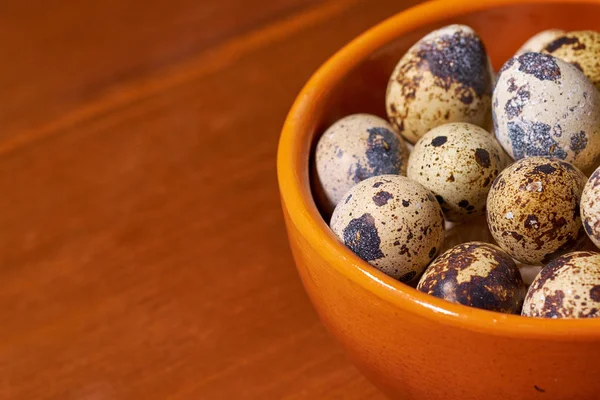 Quail eggs in clay bowl on brown wooden background. Selective focus — Stock Photo, Image