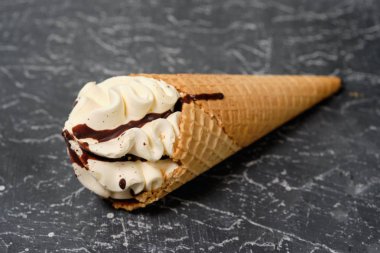 vanilyalı dondurma waffle koni koyu gri arka plan üzerine çikolata sosu ile