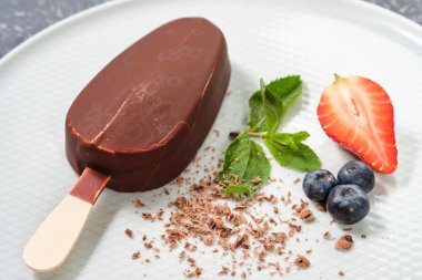 taze yaz çilek, çilek, yaban mersini ile beyaz tabakta çikolata tereyağı dondurma popsicles