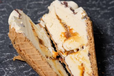 vanilyalı dondurma waffle koni ile koyu gri arka planda bir kesim karamel
