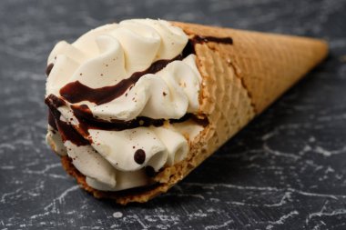 vanilyalı dondurma waffle koni koyu gri arka plan üzerine çikolata sosu ile