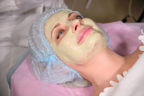 Cosmetologist making a face mask to her patient  . Anti-ageing and smoothing procedure in a beauty salon. Doctor in a cosmetological clinic making a treatment of skin care