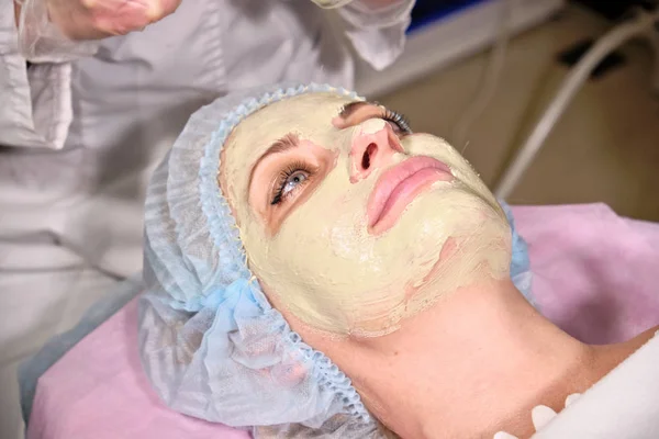 Cosmetóloga haciendo una máscara facial a su paciente. Procedimiento anti-envejecimiento y suavizado en un salón de belleza. Médico en una clínica cosmetológica haciendo un tratamiento del cuidado de la piel — Foto de Stock