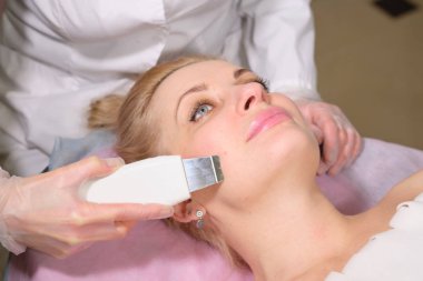 Kozmetolog hasta yüz için donanım prosedürleri yapmak. Bir güzellik salonunda yaşlanma karşıtı ve yumuşatma prosedürü. Doktor bir kozmetik klinikte cilt bakımı bir tedavi yapma